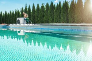 Outdoor Swimming Pool Heating by Heat Pump. HVAC Technician Testing New Device Next to the Pool.